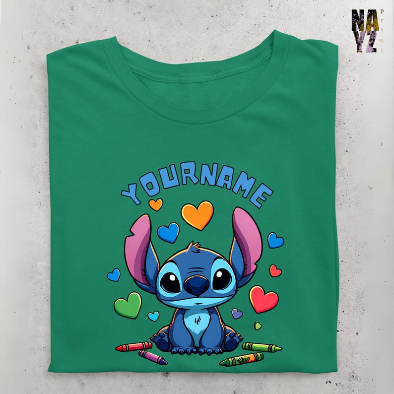 K&ouml;nnte beinhalten: Ein gr&uuml;nes T-Shirt mit einer blauen Stitch-Figur aus Lilo & Stitch. Stitch ist von bunten Herzen und Buntstiften umgeben. Der Text "YOUR NAME" befindet sich &uuml;ber Stitch.