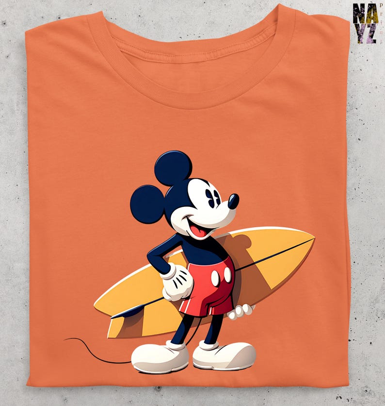 Op de afbeelding: Oranje t-shirt met een cartoonafbeelding van Mickey Mouse met een geel surfboard. Mickey draagt een rode korte broek, witte handschoenen en schoenen. Het shirt heeft een ronde hals en is opgevouwen.