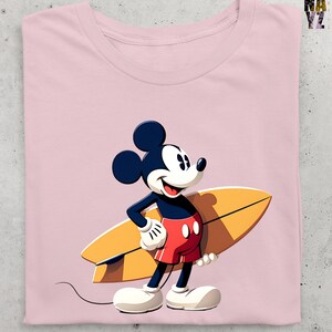 Op de afbeelding: Roze T-shirt met een cartoonafbeelding van Mickey Mouse met een gele surfplank. Mickey draagt een rode korte broek, witte handschoenen en schoenen. Het shirt heeft een ronde hals en korte mouwen. Het ontwerp is gecentreerd.