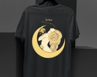 May include: Black t-shirt featuring a gold illustration of the Aries zodiac sign. The design includes a figure embracing a ram's horn, set within a crescent moon, with the word "Aries" above. The shirt is hanging on a black hanger.