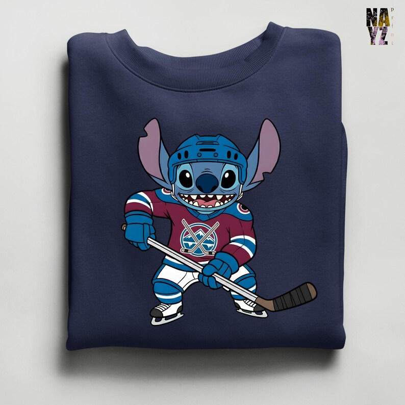 Puede incluir: Sudadera azul marino con un personaje de dibujos animados con uniforme de hockey. El personaje es azul con orejas grandes y sostiene un palo de hockey. El uniforme es burdeos, azul y blanco, con un logotipo del equipo en el pecho.