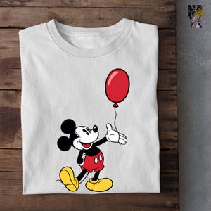 May include: A white t-shirt with a cartoon image of Mickey Mouse holding a red balloon.