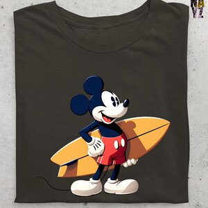 Op de afbeelding: Donker olijfgroen t-shirt met een cartoon Mickey Mouse karakter met een gele surfplank. Mickey draagt een rode korte broek, witte handschoenen en schoenen. Het shirt heeft een klassieke ronde hals.
