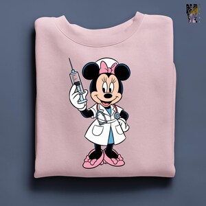 Peut inclure: Sweat-shirt rose clair avec Minnie Mouse en infirmi&egrave;re. Minnie porte une blouse blanche, un n&oelig;ud rose et tient une seringue. Le design comprend un st&eacute;thoscope et des chaussures roses.