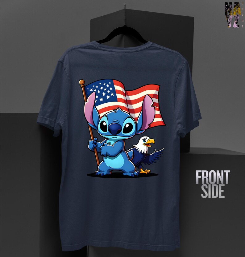 May include: Navy blue t-shirt featuring a cartoon character holding an American flag with an eagle. The character is blue with large ears. The flag has red and white stripes and a blue field with white stars. The eagle is white, blue, and yellow.