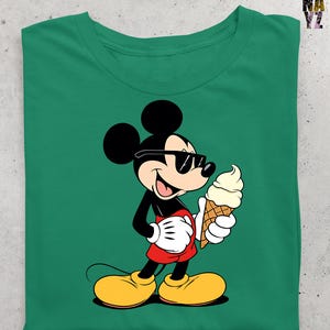 Puede incluir: Camiseta verde con una ilustraci&oacute;n de dibujos animados de Mickey Mouse con gafas de sol y un cono de helado. Mickey Mouse est&aacute; representado con su atuendo cl&aacute;sico: pantalones cortos rojos, zapatos amarillos y guantes blancos.