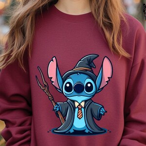K&ouml;nnte beinhalten: Ein maroonfarbener Pullover mit einem Cartoon-Bild von Stitch, der als Zauberer verkleidet ist. Stitch tr&auml;gt einen spitzen Hut, eine lange Robe und h&auml;lt einen Zauberstab.