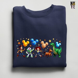 Puede incluir: Sudadera azul marino con un gr&aacute;fico colorido de personajes de una popular pel&iacute;cula animada. El dise&ntilde;o incluye a Woody, Buzz Lightyear, Jessie, un caballo y un dinosaurio verde, con globos con forma de Mickey Mouse y estrellas.
