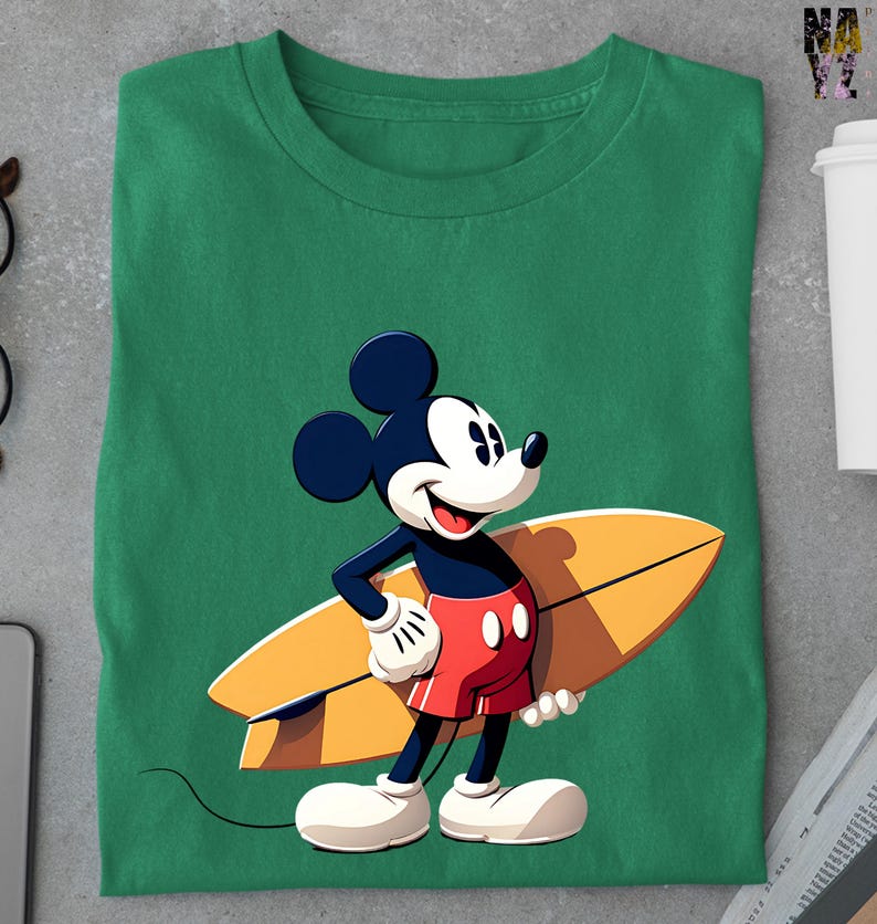 Op de afbeelding: Groen t-shirt met een cartoon illustratie van Mickey Mouse met een surfboard. Mickey draagt een rode broek, witte handschoenen en witte schoenen. Het surfboard is geel en bruin.