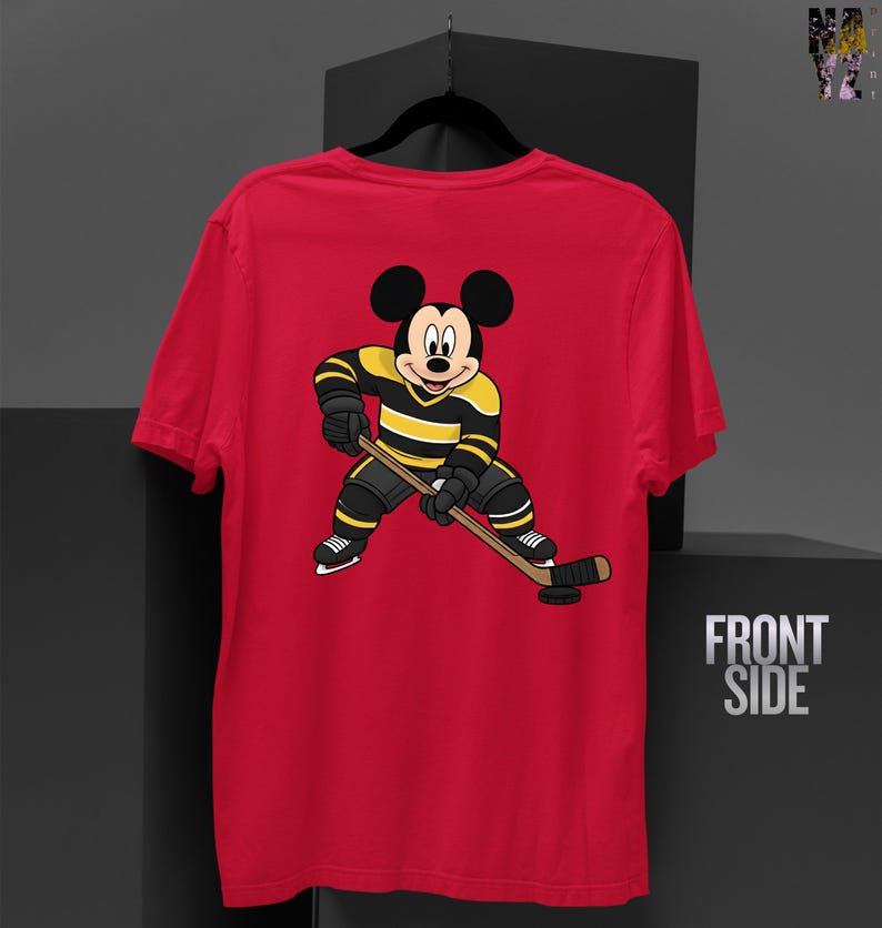 May include: Red t-shirt featuring a cartoon Mickey Mouse character in hockey gear, holding a hockey stick and puck. The character is wearing a black and yellow striped jersey and black shorts. The words "FRONT SIDE" are visible on the right.