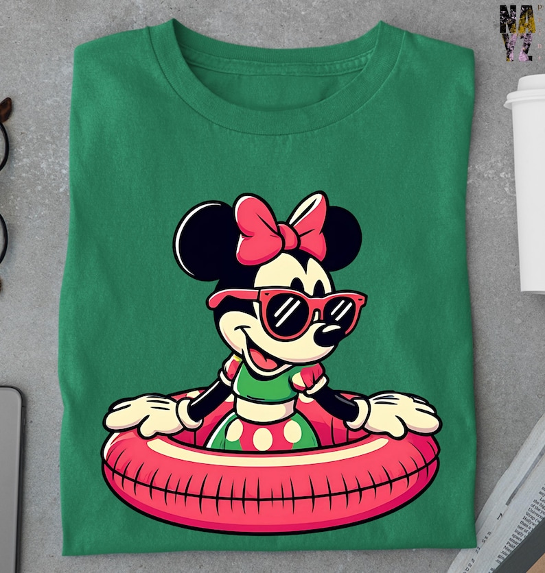 May include: Green t-shirt with a cartoon Minnie Mouse design. Minnie is wearing sunglasses and a pink bow, and is in a red and pink inflatable ring. The design is centered.