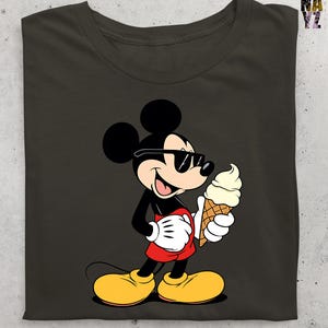 Puede incluir: Camiseta gris oscuro con un dibujo animado de Mickey Mouse con gafas de sol y un cono de helado. Mickey lleva su atuendo cl&aacute;sico: pantalones cortos rojos, zapatos amarillos y guantes blancos. La camiseta tiene cuello redondo.