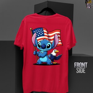May include: Red t-shirt featuring a cartoon character holding an American flag with an eagle. The character is blue with large ears. The flag has red and white stripes and a blue field with white stars. The shirt has the words "FRONT SIDE" on the side.