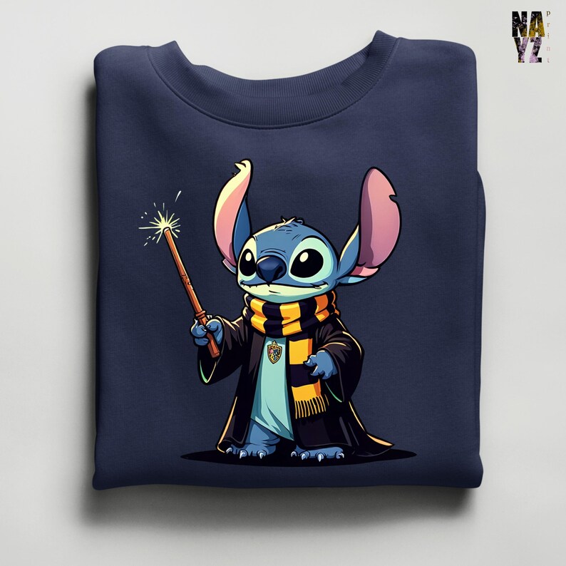 Pode incluir: Camisola azul marinho com uma ilustra&ccedil;&atilde;o de desenho animado de Stitch vestido de mago, segurando uma varinha com um efeito brilhante. Stitch est&aacute; usando uma t&uacute;nica preta e um cachecol com listras amarelas e pretas. A camisola est&aacute; dobrada.