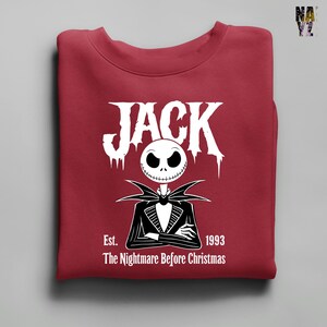 Puede incluir: Una sudadera granate con un dise&ntilde;o de Jack Skellington de "Pesadilla antes de Navidad". El dise&ntilde;o incluye la palabra "JACK", la cara del personaje y el texto "Est. 1993 The Nightmare Before Christmas."