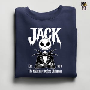 Puede incluir: Sudadera azul marino con un dise&ntilde;o blanco de Jack Skellington de Pesadilla antes de Navidad. El dise&ntilde;o incluye el nombre "JACK", la cara del personaje y el texto "Est. 1993 The Nightmare Before Christmas."