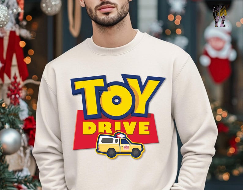 May include: A white sweatshirt with a yellow and blue "Toy Drive" graphic. The graphic features a cartoon toy truck with a pizza delivery logo.