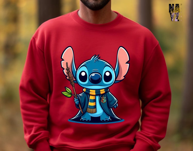 May include: Red sweatshirt with a blue cartoon character wearing a yellow and black scarf and a black robe. The character is holding a stick and has large blue eyes.