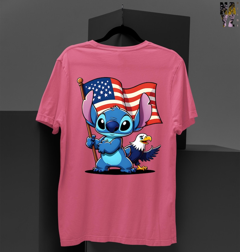 May include: Pink t-shirt featuring a cartoon Stitch character holding an American flag with an eagle. The design includes red, white, and blue colors. The shirt is a crew neck style.