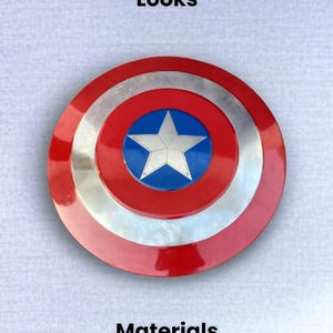 May include: A Captain America shield with a red, silver, and blue color scheme. The shield features a central blue circle with a white star, surrounded by silver and red concentric rings. The text "Captain America Shield Fully Original Looks" is at the top.