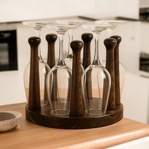 May include: A dark wood wine glass holder with eight clear wine glasses. The holder has a circular base and individual slots for each glass. The wooden stems are cylindrical and the base is a dark brown colour.