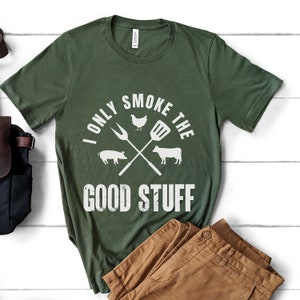 May include: A green t-shirt with the text "I only smoke the good stuff" in white. The text is surrounded by a graphic of a chicken, pig, cow, and crossed grilling tools.