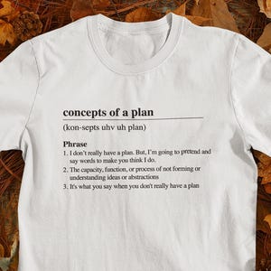 May include: White t-shirt with black text that reads "concepts of a plan (kon-septs uhv uh plan)" and a definition of the phrase in three bullet points.