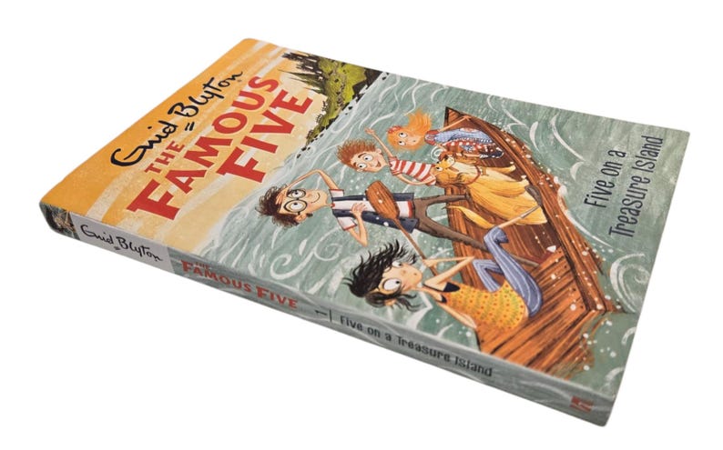 May include: A hardcover book titled "The Famous Five" by Enid Blyton. The cover features an illustration of five children in a boat on water. The book's title is in large red letters, with the author's name in a smaller font.