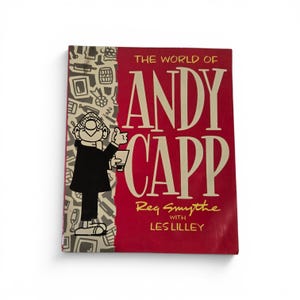 May include: A book titled The World of Andy Capp by Reg Smythe with Les Lilley. The cover features a red background with large cream-colored text and a black and white illustration of the character Andy Capp on a patterned side panel.