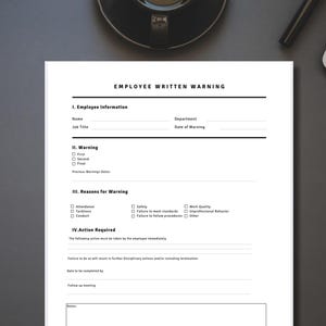 May include: A white Employee Written Warning form with black text. The form includes sections for employee information, warnings, reasons for warning, and required actions. The form is on a dark gray surface.