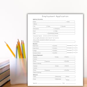 May include: A white employment application form with sections for personal details, education, and work history. The form includes fields for name, address, and employment details. Pencils and books are in the background.