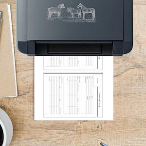 May include: A black printer with a horse illustration is printing a livestock log. The log is a two-page document with columns and rows for recording information. A pen and a cup are on the wooden surface.