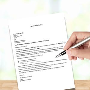 May include: A white sheet of paper with the words "Termination Notice" at the top. The document is being held by a person's hand, with a pen poised above the text. The document contains text regarding a boarding agreement.