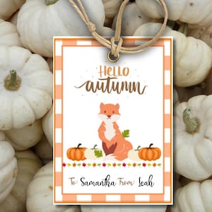 May include: A white and orange gift tag with a chequered background. The tag features a cartoon fox, pumpkins, and the text "Hello autumn". The tag also includes the text "To: Samantha From: Leah".
