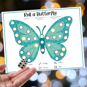 May include: A printed game sheet titled "Roll a Butterfly" featuring a teal butterfly design with colored circles. A die is being rolled to determine the color to fill in the circles. The game includes color matching.