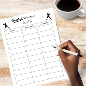 May include: A white sheet of paper with the words "Baseball Volunteer Sign Up" printed on it. The paper has a table with columns for name, phone/email, and availability. A hand is holding a pen over the paper. A cup of coffee is in the background.