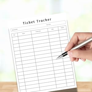 Può includere: Un foglio di carta bianco intitolato "Ticket Tracker" con una griglia per tenere traccia delle informazioni. Una penna d'argento è tenuta sopra la carta, pronta per scrivere. La parte superiore del foglio ha il titolo e spazi per "Sponsored By" e "Draw Date".