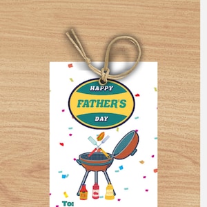 Peut inclure: Une carte blanche avec un cercle jaune et bleu qui dit "Joyeuse fête des pères". Il y a un barbecue rouge et brun avec un hot-dog, une spatule et une fourchette sur le dessus. Il y a des confettis rouges, jaunes, bleus et violets sur la carte. La carte dit "À:" et "De:" en bas.