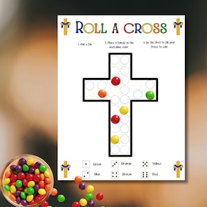 May include: A white game board with the text "ROLL A CROSS" and a cross-shaped game area. Colorful candies are scattered around a clear bowl. The game instructions are also visible.