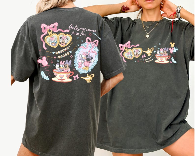 May include: Dark grey t-shirt with a colourful graphic of Disney characters, including Minnie and Daisy Mouse, teacups, and bows. The text "Girls just wanna have fun" is also visible. The shirt has a relaxed fit.
