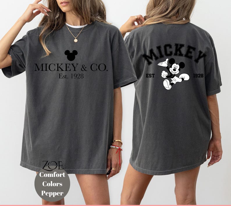 Puede incluir: Una camiseta gris de gran tama&ntilde;o con un gr&aacute;fico de Mickey Mouse negro y el texto "Mickey & Co. Est. 1928" en la parte delantera. La parte posterior de la camiseta tiene un gr&aacute;fico de Mickey Mouse negro y el texto "Mickey Est. 1928".