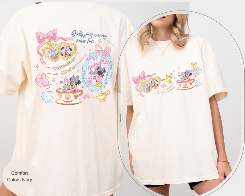 May include: Cream-coloured t-shirt with a vibrant graphic of Minnie Mouse and Daisy Duck. The design includes the text "Girls just wanna have fun" and decorative elements such as bows, teacups, and jewellery. The shirt has short sleeves and a relaxed fit.