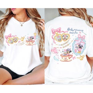 May include: White t-shirt with a cartoon design of Minnie and Daisy Mouse. The front design includes Minnie and Daisy in a teacup, and the back says "Girls just wanna have fun."