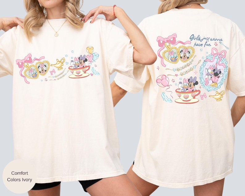 May include: Ivory t-shirt with a colourful graphic of Minnie and Daisy Mouse in teacups and heart-shaped lockets. The back of the shirt has the text "Girls just wanna have fun" with additional graphics. The shirt is a comfort fit.