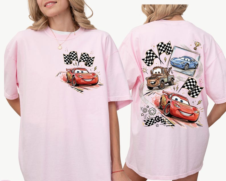 Puede incluir: Camiseta rosa claro con un dise&ntilde;o de dibujos animados de un coche de carreras rojo y banderas a cuadros. La parte trasera de la camiseta muestra m&aacute;s coches de carreras y banderas. El estilo es de dibujos animados.
