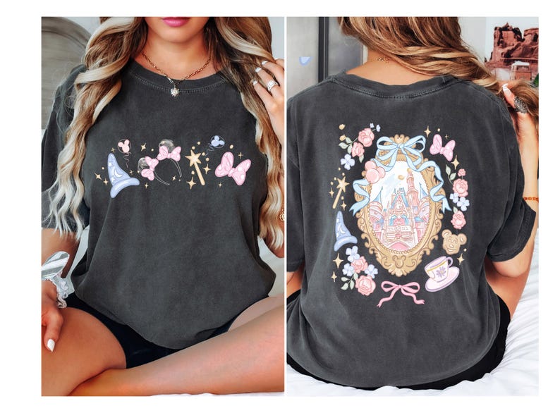 May include: Dark grey t-shirt featuring a whimsical design with a magic wand, Minnie Mouse ears, butterflies, and a wizard hat on the front. The back showcases a castle within a decorative frame, surrounded by flowers and bows.