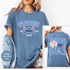 Puede incluir: Una camiseta azul con un gráfico de Stitch de Lilo & Stitch. La parte delantera de la camiseta dice "Stitch Est. 2002" y la parte trasera de la camiseta tiene un gráfico de Stitch sosteniendo un montón de globos coloridos. La camiseta es un jean azul de colores cómodos.