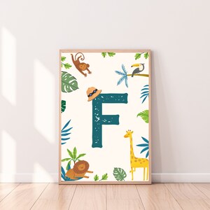 Puede incluir: Un estampado enmarcado con la letra "F" en color turquesa, rodeado de ilustraciones de la jungla. Se representan un mono, un tucán, una jirafa y un león entre hojas tropicales y un sombrero de safari. El fondo es de color crema.