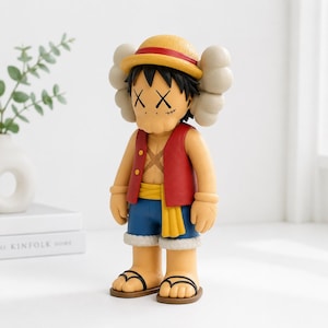 May include: A collectible vinyl figure of a character wearing a yellow straw hat with a red band, a red open vest, blue shorts with a yellow sash, and sandals. The figure features black hair, X-shaped eyes, and a cross-shaped scar on the chest.
