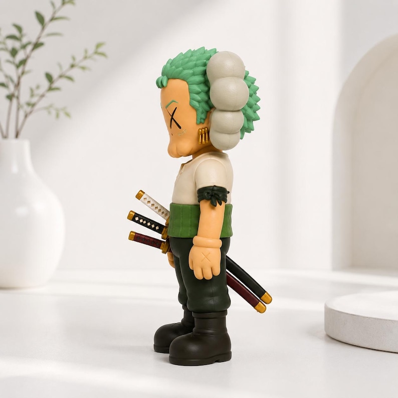 May include: A stylized vinyl collectible figure featuring green hair, a tan complexion, and X-shaped eyes. The figure wears a white shirt, a green sash, dark pants, and black boots, with three swords strapped to its back and gold earrings.